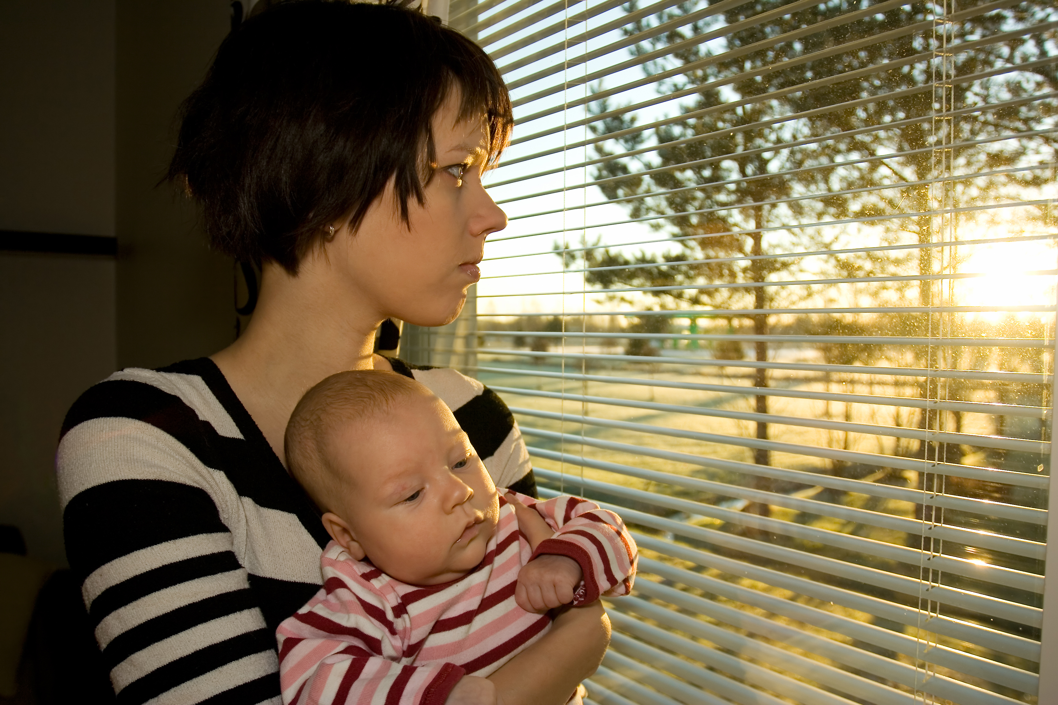 Young mother looking out from the window with her baby 2 - ABCD Action for  Boston Community Development