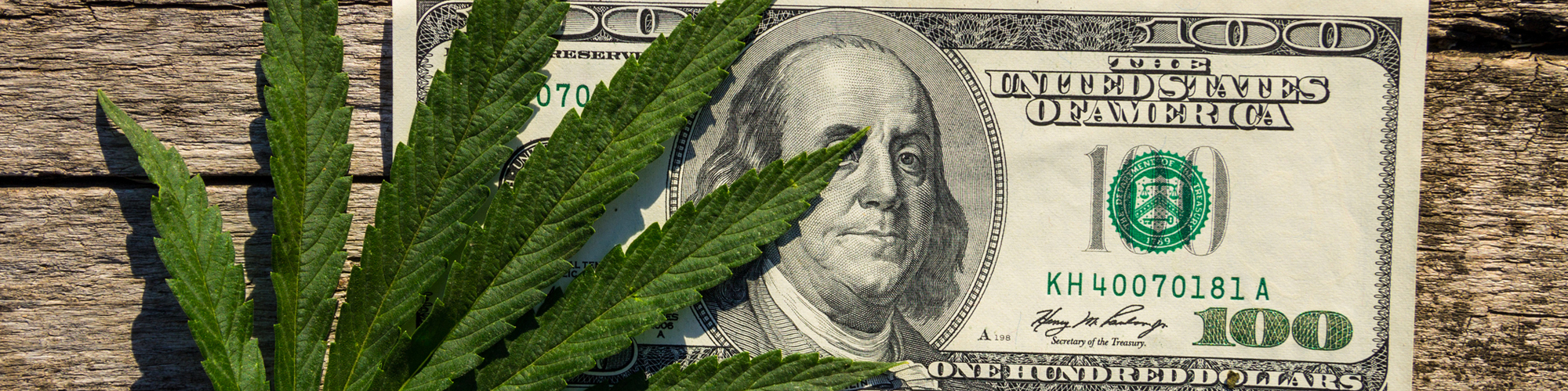 $100 bill with a cannabis leaf on a wooden background